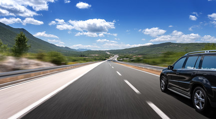 Dark car on a freeway in a beautiful area.