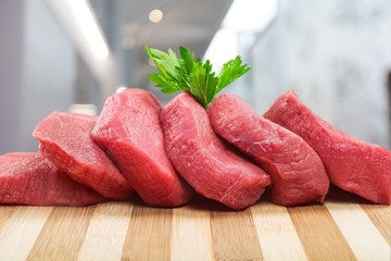 Raw Meat slices and knife on cutting board