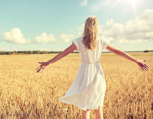 Fototapeta na wymiar country, nature, summer holidays, vacation and people concept - happy young woman in white dress on cereal field