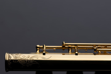 A shiny gold plated flute with an engraving on a reflective surface. An instrument common in a...