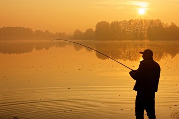 fisherman silhouette in the lake during sunrise
