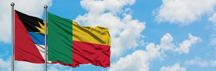Obraz premium Antigua and Barbuda with Benin flag waving in the wind against white cloudy blue sky together. Diplomacy concept, international relations.
