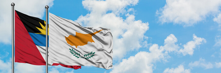 Antigua and Barbuda with Cyprus flag waving in the wind against white cloudy blue sky together. Diplomacy concept, international relations.