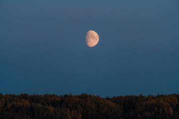 Alaskan mountains with half moon and pink skies after sunset during blue hour