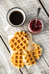 Tasty sweet waffles with raspberry jam and tea cup.