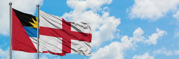 Antigua and Barbuda with England flag waving in the wind against white cloudy blue sky together. Diplomacy concept, international relations.