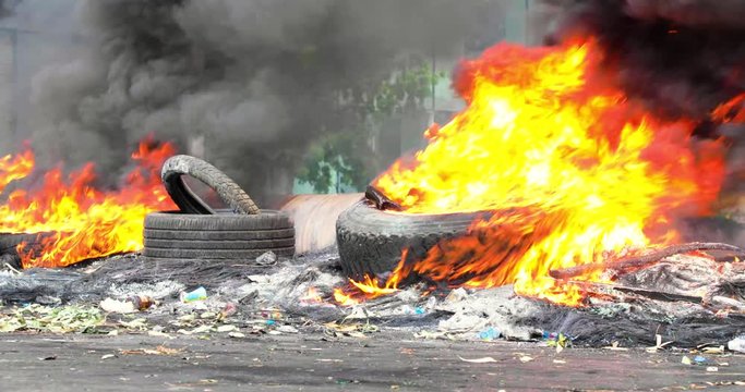 Tires burning in a street during a riot. Flames and black smoke rise into the air