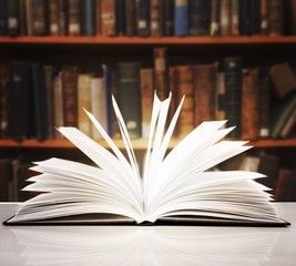 Fototapeta premium Old open book on a bookshelf background.