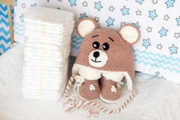 diapers with baby soft clothes for newborns bear on the background of the nursery and crib, the concept of using diapers for babies