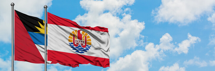 Antigua and Barbuda with French Polynesia flag waving in the wind against white cloudy blue sky together. Diplomacy concept, international relations.