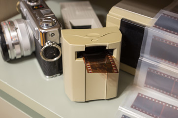 professional film scanner, vintage camera and film segments in the background, film photography, film digitization