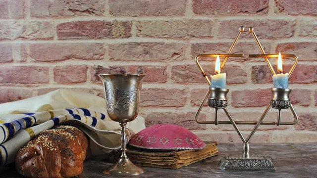 Shabbat eve table with covered challah bread, candles and cup of wine.