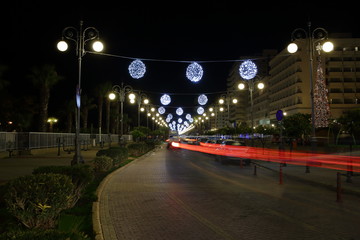 Fototapeta premium traffic in the city at night, street decorated with Christmas lights, red trails of car lights