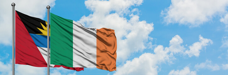 Antigua and Barbuda with Ireland flag waving in the wind against white cloudy blue sky together. Diplomacy concept, international relations.