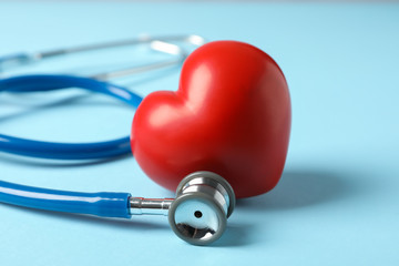 Stethoscope and heart on blue background, close up