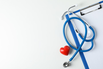 Stethoscope, tablet and heart on white background, space for text