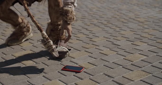 Surprised neanderthal of hunter-gatherers found the phone discovering modern device exploring future civilization device evolution future homo sapiens caveman ancient slow motion