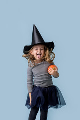 Little girl with a pumpkin in hands and in a witch costume