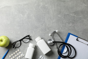 Fototapeta na wymiar Stethoscope and medicines on grey background, top view. Doctor workplace