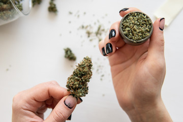 Close up of marijuana blunt with grinder. Woman preparing and rolling marijuana cannabis joint....