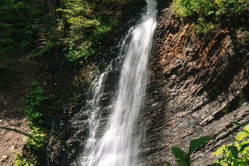 Beautiful waterfall in summer. A fast waterfall. View of the waterfall from below