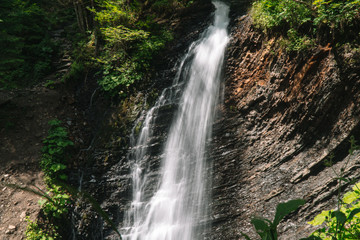 Beautiful waterfall in summer. A fast waterfall. View of the waterfall from below