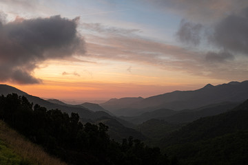 Orange sunrise on a cloudy sky and black mountain silhouette on a spectacular colourful sky