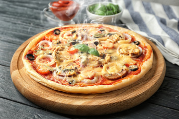Board with tasty pizza on wooden table