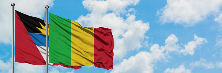 Fototapeta premium Antigua and Barbuda with Mali flag waving in the wind against white cloudy blue sky together. Diplomacy concept, international relations.