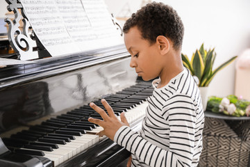 Little African-American boy playing grand piano at home © Pixel-Shot