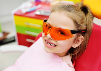 Little girl sitting on dental chair in pediatric dentists office.