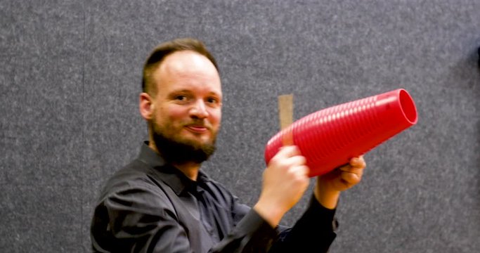 Happy young adult musician playing and scrapping the guiro. Latin percussion instrument often used in bossa nova music