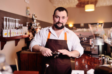a handsome, bearded barista man holding a Holder with ground coffee. Making coffee in a coffee house
