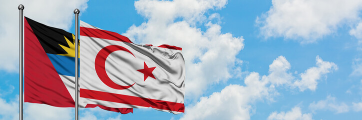 Antigua and Barbuda with Northern Cyprus flag waving in the wind against white cloudy blue sky together. Diplomacy concept, international relations.