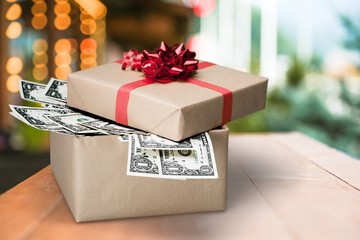 Christmas present with red bow wrapped in dollar banknotes isolated on white background