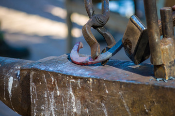 blacksmith performs the forging of hot glowing horseshoe on the anvil