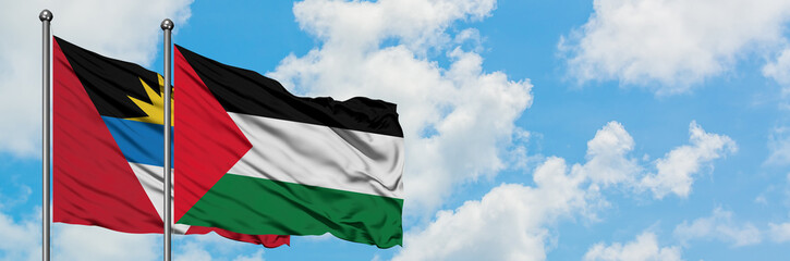 Antigua and Barbuda with Palestine flag waving in the wind against white cloudy blue sky together. Diplomacy concept, international relations.