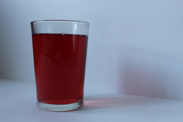 a glass of red juice from strawberries raspberries cherries or wine on a white background