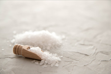 Sea salt crystals in wooden scoop close-up on concrete background. Small shovel with sea salt. Copy space