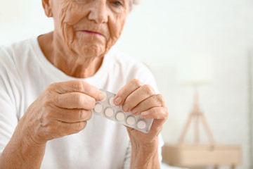 Elderly woman with pills at home