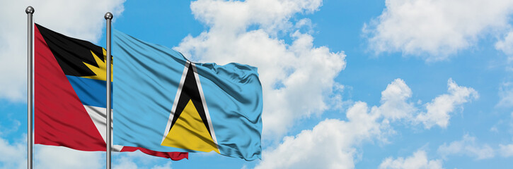 Antigua and Barbuda with Saint Lucia flag waving in the wind against white cloudy blue sky together. Diplomacy concept, international relations.