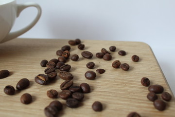 whole Arabica coffee beans and a Cup of coffee on a Board with a white background
