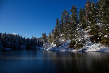 Frozen lake in evergreen forest on a cold sunny winter day