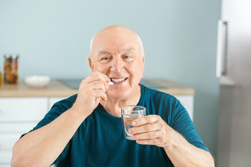 Elderly man taking medicine at home