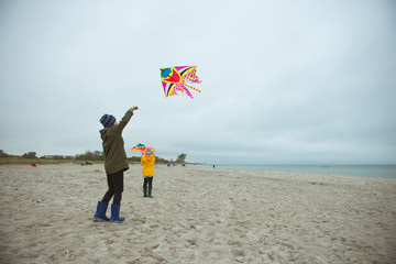 Teen brother and sister playing with kites in sand dunes of Baltic coastline