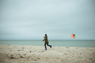 Teen brother and sister playing with kites in sand dunes of Baltic coastline