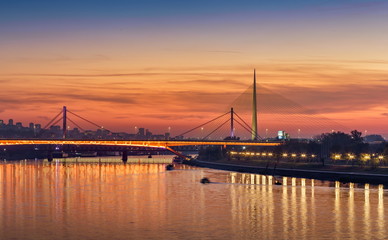 Fototapeta na wymiar Belgrade Bridges on Sava River, Gazela, Railway Bridge, Ada Bridge Sunset City Lights Water Reflections