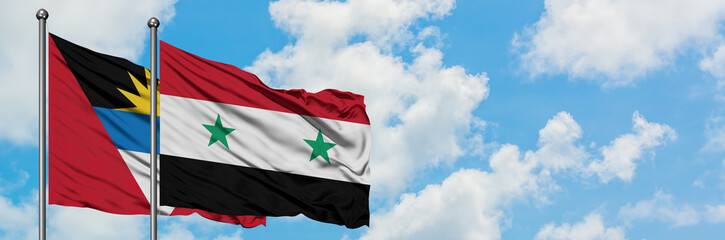 Antigua and Barbuda with Syria flag waving in the wind against white cloudy blue sky together. Diplomacy concept, international relations.