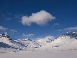Verschneite Berglandschaft mit einzelnen Wolken