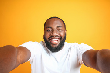 Happy African-American man taking selfie on color background